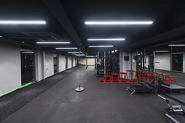 Image showing An empty modern gymnasium with a variety of equipment, offering a spacious, functional, and well-equipped training facility for workouts, fitness, and strength training