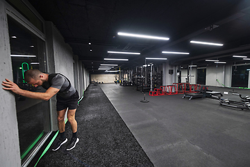 Image showing A muscular man is focused on working out with dumbbells in a modern gym, showing his determination and commitment to his fitness regimen.