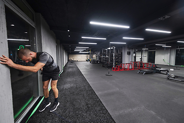 Image showing A muscular man is focused on working out with dumbbells in a modern gym, showing his determination and commitment to his fitness regimen.