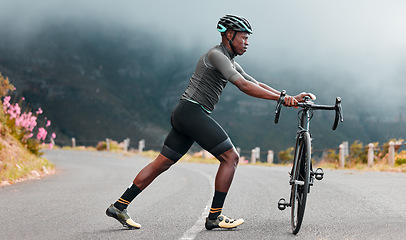 Image showing Stretching legs, fitness and man cycling on a road with a bike in the mountains for cardio, travel and sports workout in nature. Athlete doing a warm up before training on a bicycle in the street