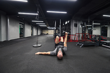 Image showing A muscular man is focused on working out with dumbbells in a modern gym, showing his determination and commitment to his fitness regimen.