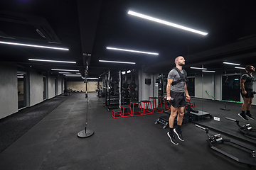 Image showing A muscular man is focused on working out with dumbbells in a modern gym, showing his determination and commitment to his fitness regimen.