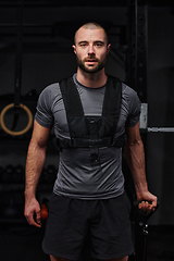 Image showing A muscular man working arm exercises in a modern gym, showcasing his strength and dedication to fitness.