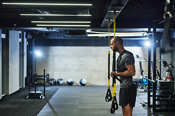 Image showing A muscular man in the gym, preparing for his workout, exudes determination and focus as he gets ready to push his limits and achieve his fitness goals.