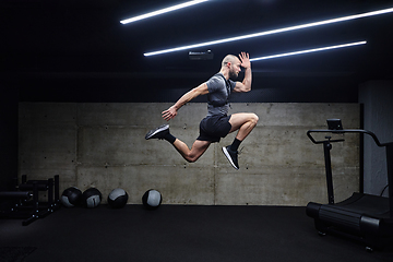 Image showing A muscular man captured in air as he jumps in a modern gym, showcasing his athleticism, power, and determination through a highintensity fitness routine