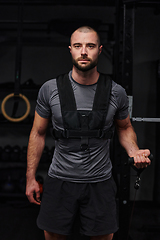 Image showing A muscular man working arm exercises in a modern gym, showcasing his strength and dedication to fitness.