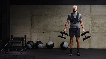 Image showing A muscular man performs shoulder exercises in a modern gym, showcasing his strength and dedication to fitness.