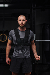 Image showing A muscular man working arm exercises in a modern gym, showcasing his strength and dedication to fitness.