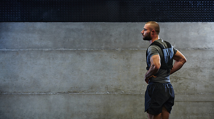 Image showing A muscular man in the gym, preparing for his workout, exudes determination and focus as he gets ready to push his limits and achieve his fitness goals.