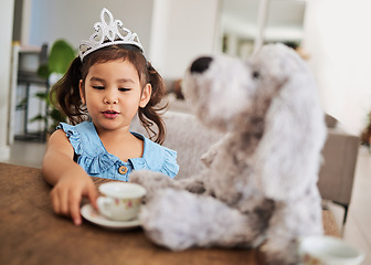 Image showing Girl, toy and tea party at a table with a princess crown, playing, having fun and talking in her home. Fantasy, creative and girl looking happy while talking to a teddy bear and drinking tea together