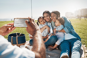 Image showing Phone, family and picnic with children, parents and grandparents posing for a photograph on a field by the beach. Kids, mobile and love with the hands of a man taking a picture of his relatives
