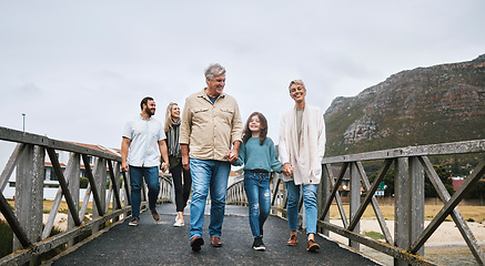 Image showing Family, walking and travel with a girl and grandparents holding hands on a pier while on holiday or vacation together. Love, trust and children with a man, woman and granddaughter boding on a walk