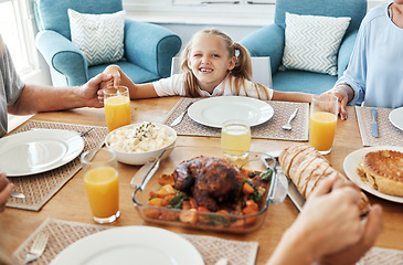 Image showing Food, family and praying with girl at a table, holding hands in gratitude, prayer and bonding before eating. Worship, pray time and child looking curious, hungry and playful while looking at a meal