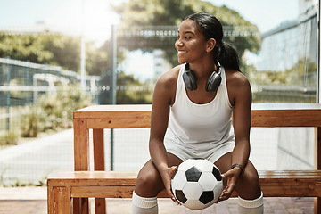 Image showing Sports, soccer and a woman on bench with ball in city park in Sao Paulo. Fitness, fun and a happy black woman in Brazil sitting, holding soccer ball and watching a game in summer sun with headphones
