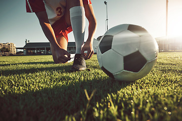 Image showing Soccer, ball and tying shoes for sports day of player on the grassy field for match, game or competition. Football professional in motivation getting ready for sport activity, fitness and exercise