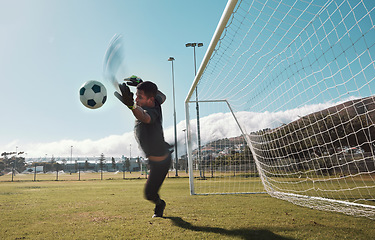 Image showing Goalkeeper, soccer and man jumping for the ball to save the goals by the score post at an outdoor field. Fitness, football and healthy male goalie playing or training with energy for the sports game.