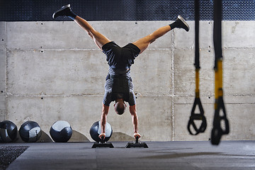 Image showing A muscular man in a handstand position, showcasing his exceptional balance and body control while performing a variety of exercises to enhance his overall body stability and strength in a modern gym