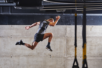 Image showing A muscular man captured in air as he jumps in a modern gym, showcasing his athleticism, power, and determination through a highintensity fitness routine