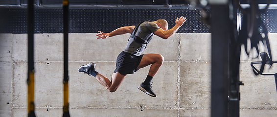 Image showing A muscular man captured in air as he jumps in a modern gym, showcasing his athleticism, power, and determination through a highintensity fitness routine