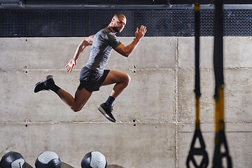 Image showing A muscular man captured in air as he jumps in a modern gym, showcasing his athleticism, power, and determination through a highintensity fitness routine