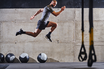 Image showing A muscular man captured in air as he jumps in a modern gym, showcasing his athleticism, power, and determination through a highintensity fitness routine