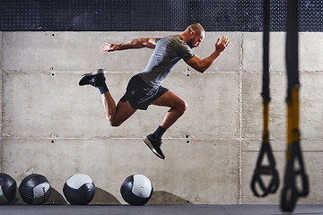 Image showing A muscular man captured in air as he jumps in a modern gym, showcasing his athleticism, power, and determination through a highintensity fitness routine