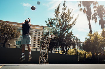 Image showing Basketball, outdoor and a man shooting ball alone on basketball court in Miami summer sun. Fitness, training and health, basketball player jumping to score on court at weekend sports game practice.