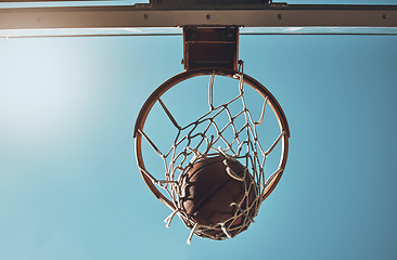 Image showing Basketball, net and ball below in sports game outdoors for sports match in the USA. Sport and airball of throw to score point for win, victory against fiberglass board with blue sky background