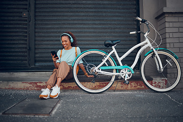 Image showing Bike, woman and headphone with phone in city relax, with bicycle and happy texting, social media apps and chat. Girl, lady and with eco friendly transportation, trendy or edgy look sit on sidewalk