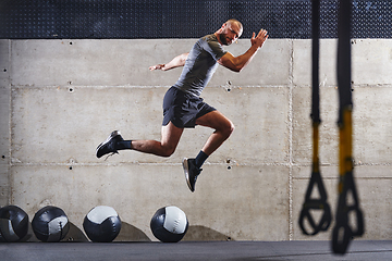 Image showing A muscular man captured in air as he jumps in a modern gym, showcasing his athleticism, power, and determination through a highintensity fitness routine