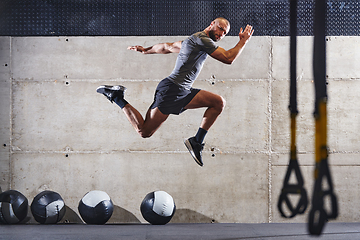 Image showing A muscular man captured in air as he jumps in a modern gym, showcasing his athleticism, power, and determination through a highintensity fitness routine