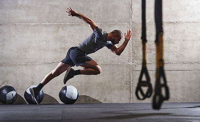 Image showing A muscular man captured in air as he jumps in a modern gym, showcasing his athleticism, power, and determination through a highintensity fitness routine