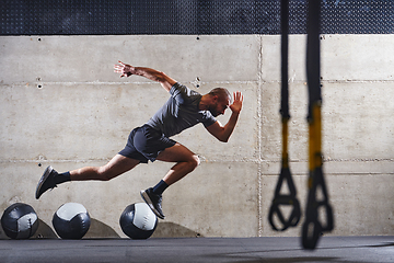 Image showing A muscular man captured in air as he jumps in a modern gym, showcasing his athleticism, power, and determination through a highintensity fitness routine