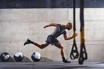 Image showing A muscular man captured in air as he jumps in a modern gym, showcasing his athleticism, power, and determination through a highintensity fitness routine