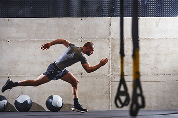 Image showing A muscular man captured in air as he jumps in a modern gym, showcasing his athleticism, power, and determination through a highintensity fitness routine