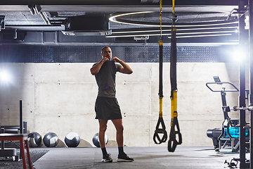 Image showing A muscular man in the gym, preparing for his workout, exudes determination and focus as he gets ready to push his limits and achieve his fitness goals.