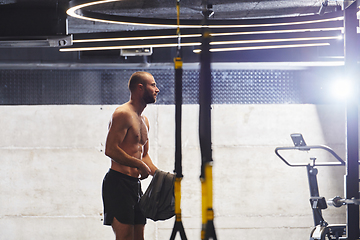 Image showing A muscular man in the gym, preparing for his workout, exudes determination and focus as he gets ready to push his limits and achieve his fitness goals.