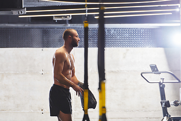 Image showing A muscular man in the gym, preparing for his workout, exudes determination and focus as he gets ready to push his limits and achieve his fitness goals.