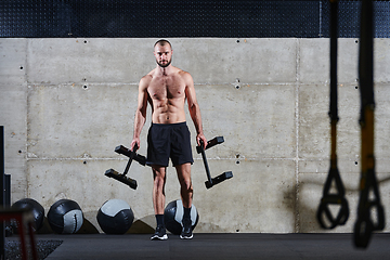 Image showing A muscular man performs shoulder exercises in a modern gym, showcasing his strength and dedication to fitness.