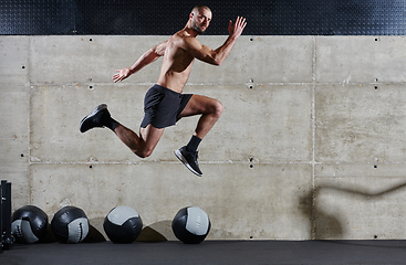 Image showing A muscular man captured in air as he jumps in a modern gym, showcasing his athleticism, power, and determination through a highintensity fitness routine