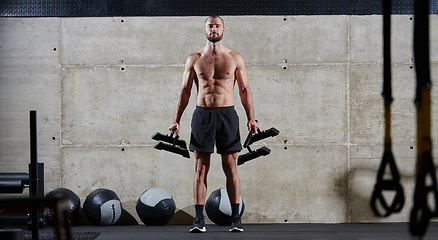 Image showing A muscular man performs shoulder exercises in a modern gym, showcasing his strength and dedication to fitness.