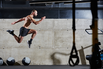 Image showing A muscular man captured in air as he jumps in a modern gym, showcasing his athleticism, power, and determination through a highintensity fitness routine