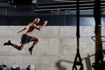 Image showing A muscular man captured in air as he jumps in a modern gym, showcasing his athleticism, power, and determination through a highintensity fitness routine