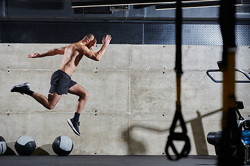 Image showing A muscular man captured in air as he jumps in a modern gym, showcasing his athleticism, power, and determination through a highintensity fitness routine