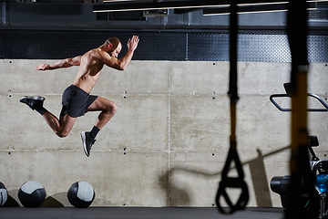 Image showing A muscular man captured in air as he jumps in a modern gym, showcasing his athleticism, power, and determination through a highintensity fitness routine