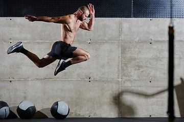 Image showing A muscular man captured in air as he jumps in a modern gym, showcasing his athleticism, power, and determination through a highintensity fitness routine