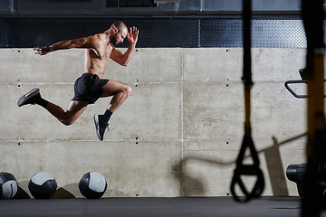 Image showing A muscular man captured in air as he jumps in a modern gym, showcasing his athleticism, power, and determination through a highintensity fitness routine