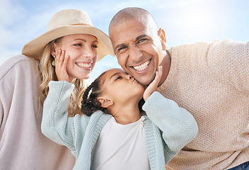 Image showing Happy family, mother and father with a kiss from a child on the face in summer outdoors on a weekend. Interracial, mama and girl loves kissing dad with a big smile on cheek on sunny holiday vacation