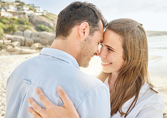 Image showing Couple, love and hug on a beach together for an engagement honeymoon or anniversary by the sea. Young man and woman smile feeling happy and romantic by the ocean water and sand with happiness