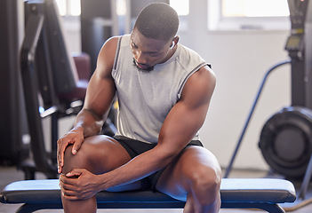 Image showing Black man, fitness and knee injury in gym after workout, training or intense exercise. Earphones, health and bodybuilder male from Nigeria suffering from sore leg, muscle pain or joint inflammation.